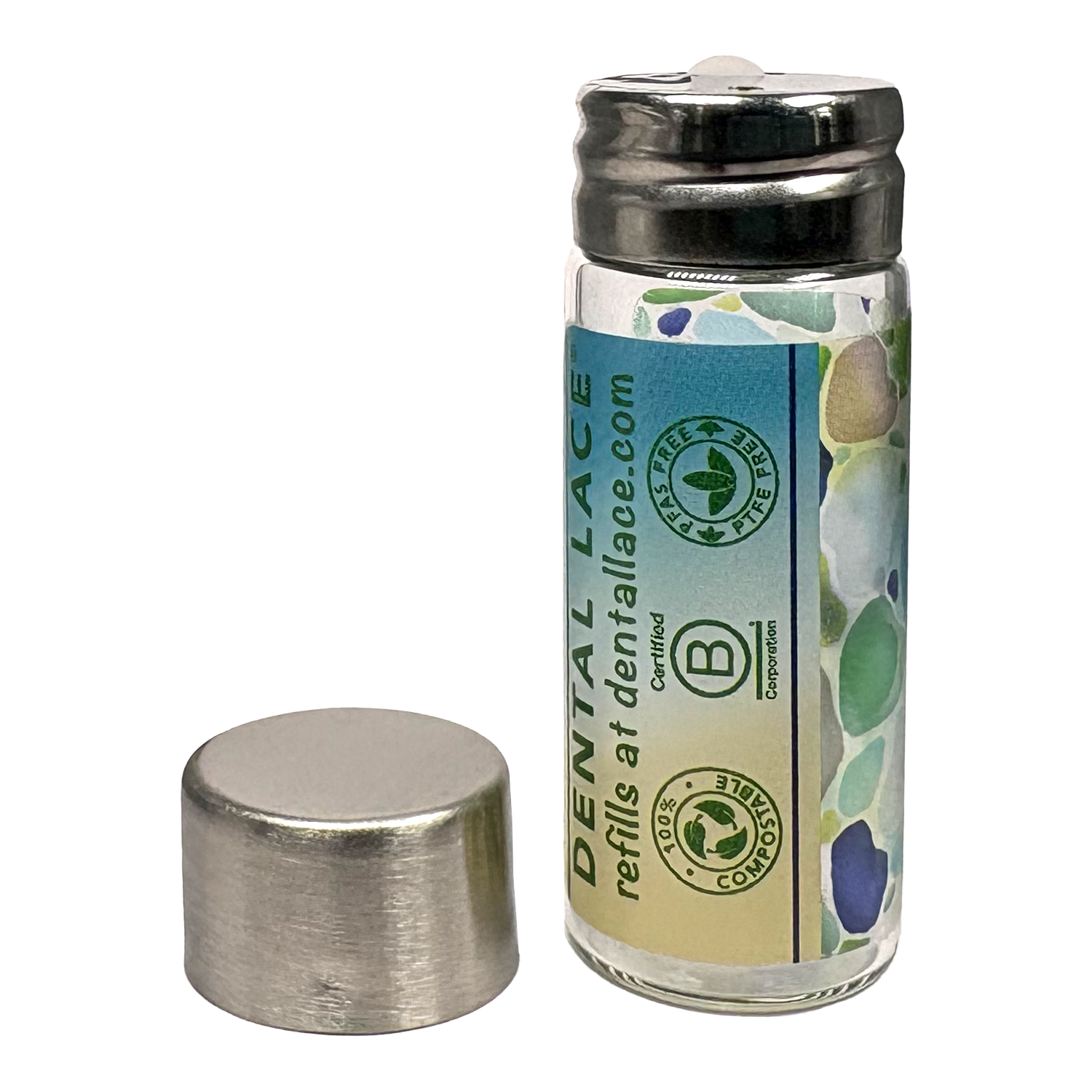 Cylindrical glass floss container with a metallic cap and beach glass ‘Dental Lace’ label on a white background.