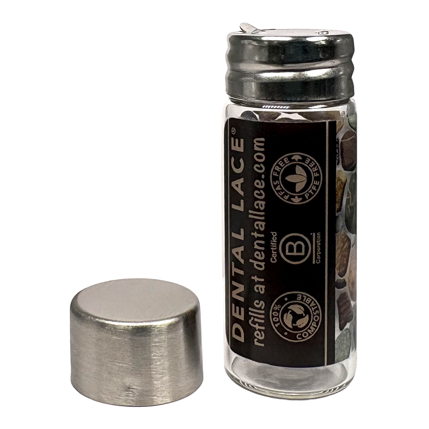 Cylindrical glass floss container with a metallic cap and pebbles ‘Dental Lace’ label on a white background.