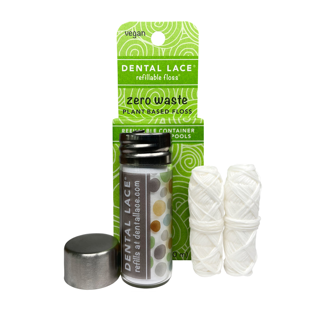 A glass container with a stainless steel cap and floss cutter, accompanied by two spools of plant-based vegan dental floss, packaged in a green cardboard box with a white design.