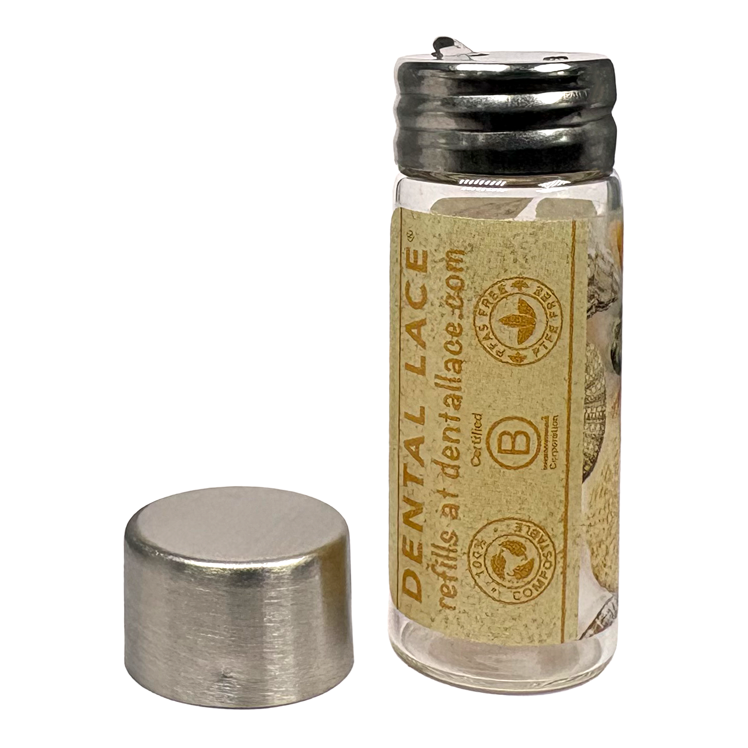 Cylindrical glass floss container with a metallic cap and seashells ‘Dental Lace’ label on a white background.