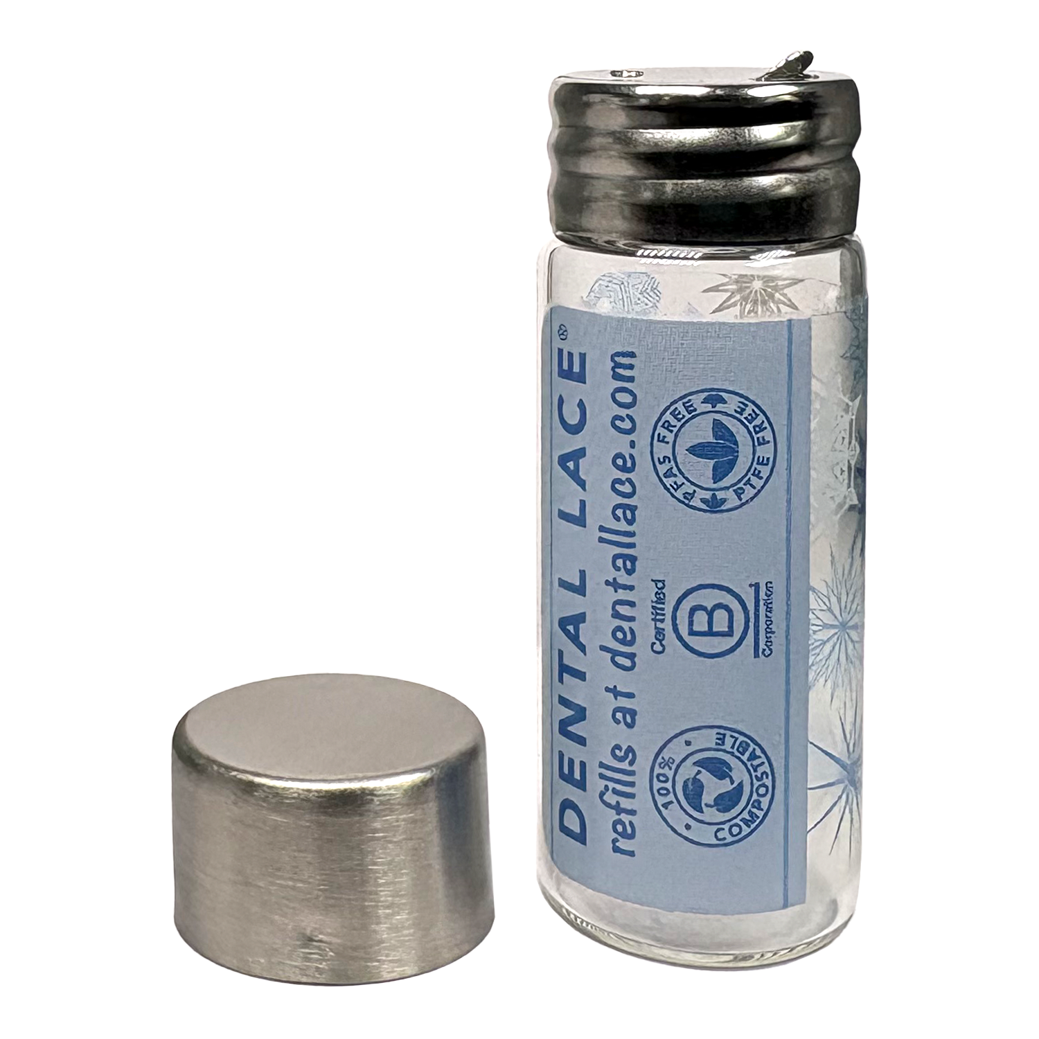 Cylindrical glass floss container with a metallic cap and snowflakes ‘Dental Lace’ label on a white background.