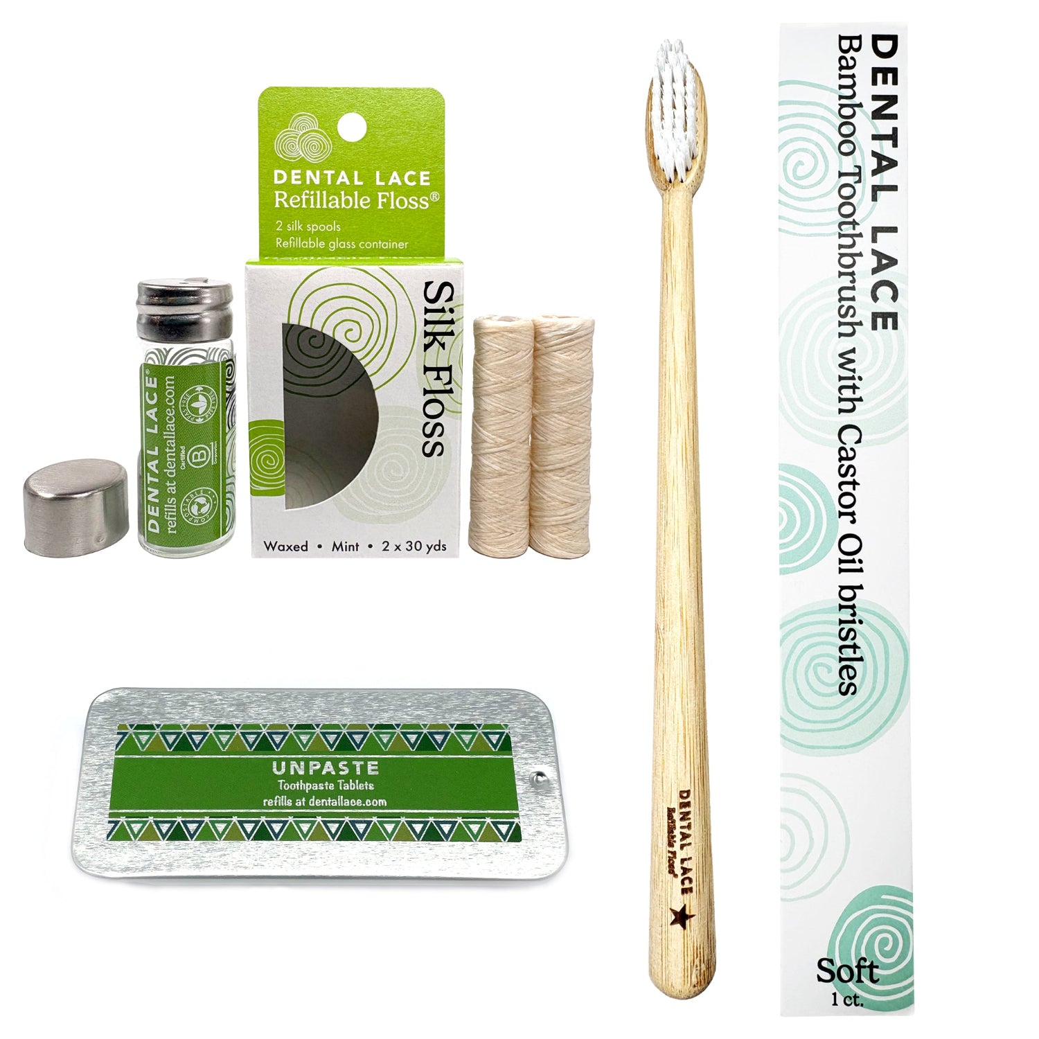 A bamboo toothbrush with a light wood handle and white bristles stands upright next to its white and green branded box. Surrounding it are included accessories: a small glass bottle of dental lace refill, a metal cap, two silk floss spools, and a silver tray with a green Unpaste toothpaste tablet packet.