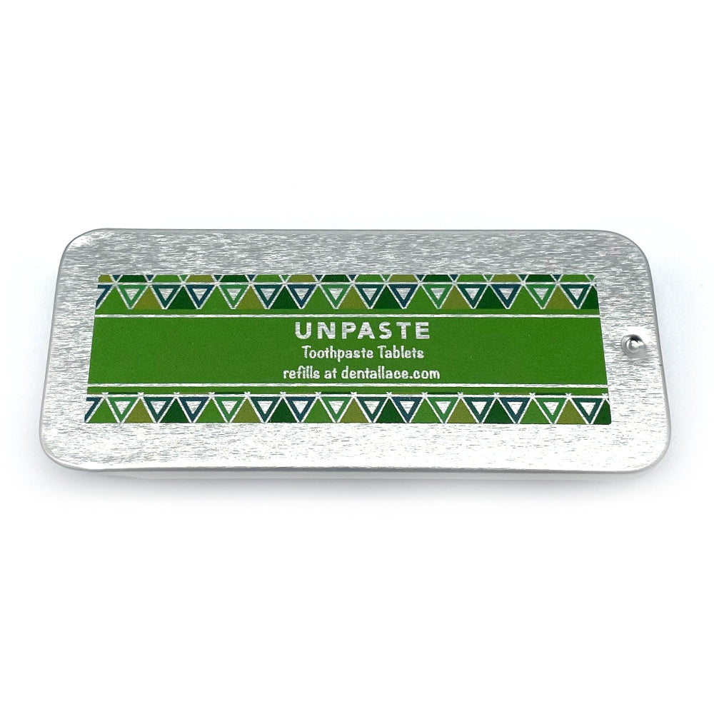 Metallic tin with unpaste fluoride free toothpaste tablets and a green design on a white background.