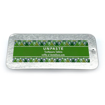 Metallic tin with unpaste fluoride free toothpaste tablets and a green design on a white background.